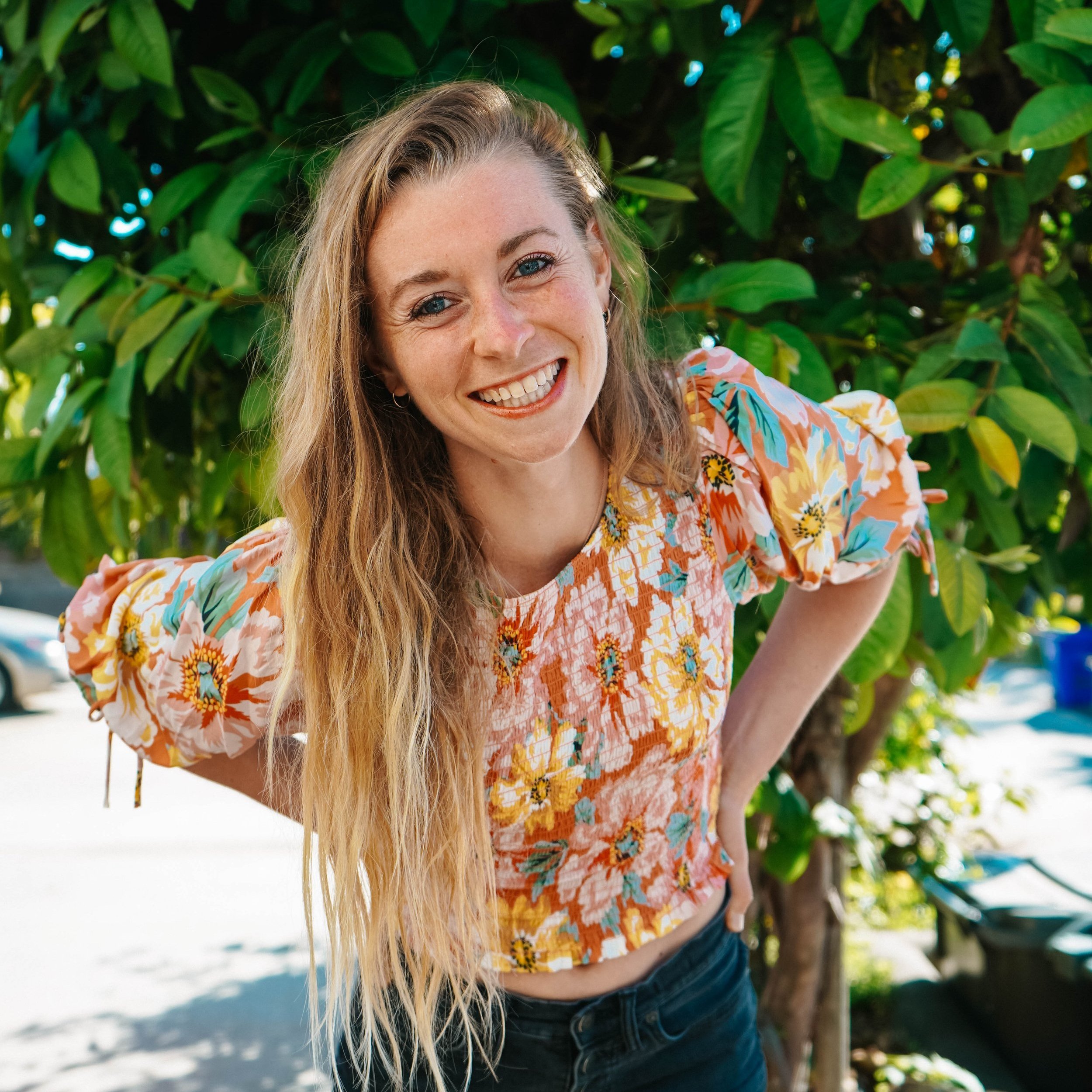 Tara Kemp smiling in a floral top in front of a tree