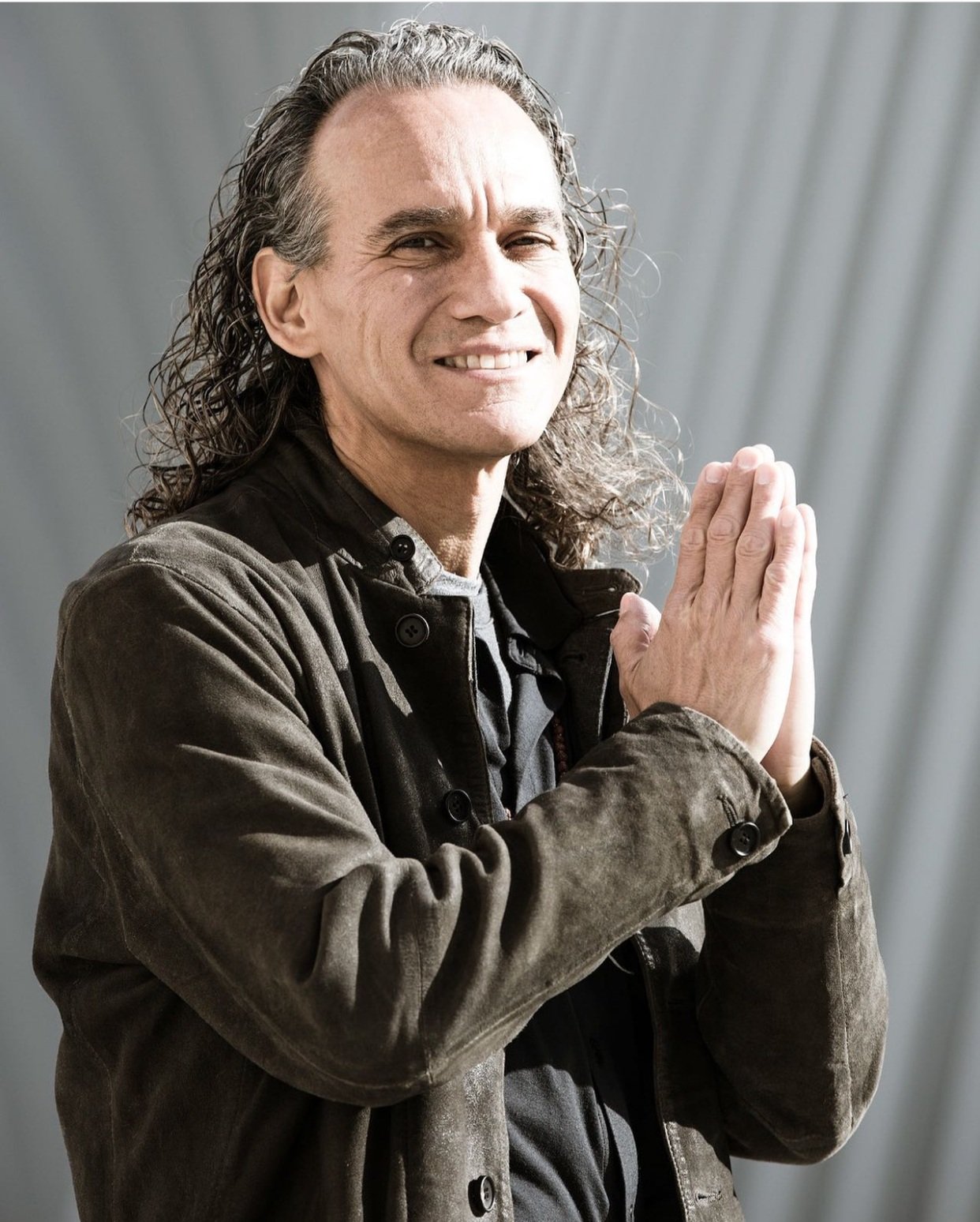 Ulises Calatayud holding his hands in a prayer position against a grey backdrop