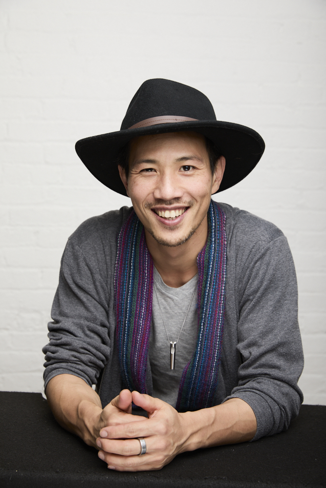 Benjamin Von Wong with hands crossed in front of him wearing a hat, multicolor scarf and gray outfit