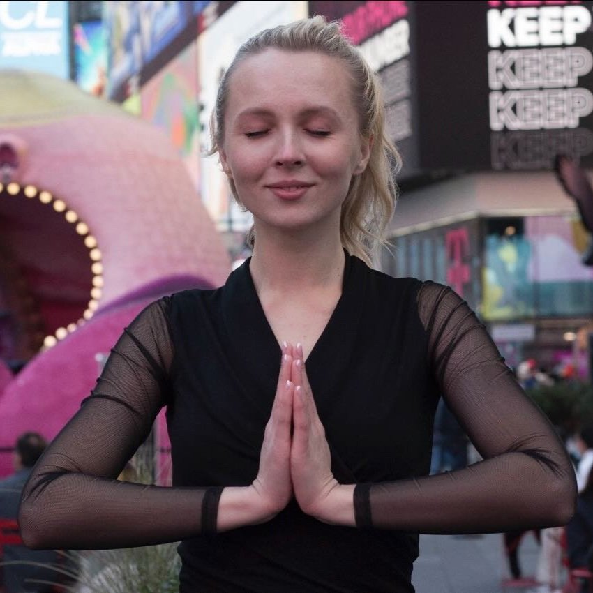 Alina Kuderska with hands in a prayer position standing in a city