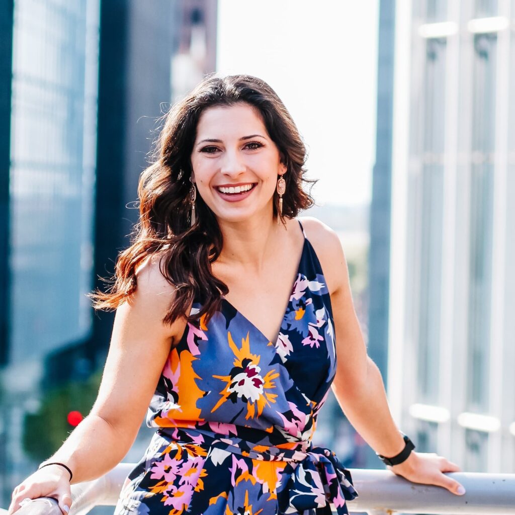 Jess Gil in a pattened dress standing in front of city skyline