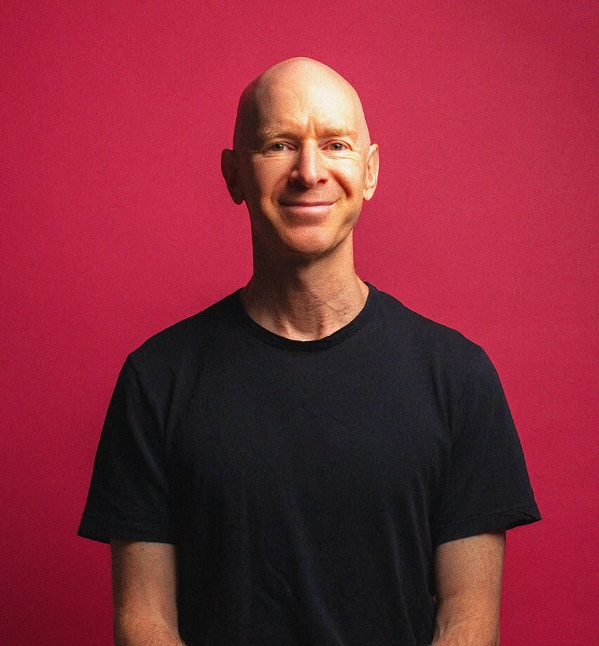 Eddie Stern sitting in a black t-shirt in front of a red background