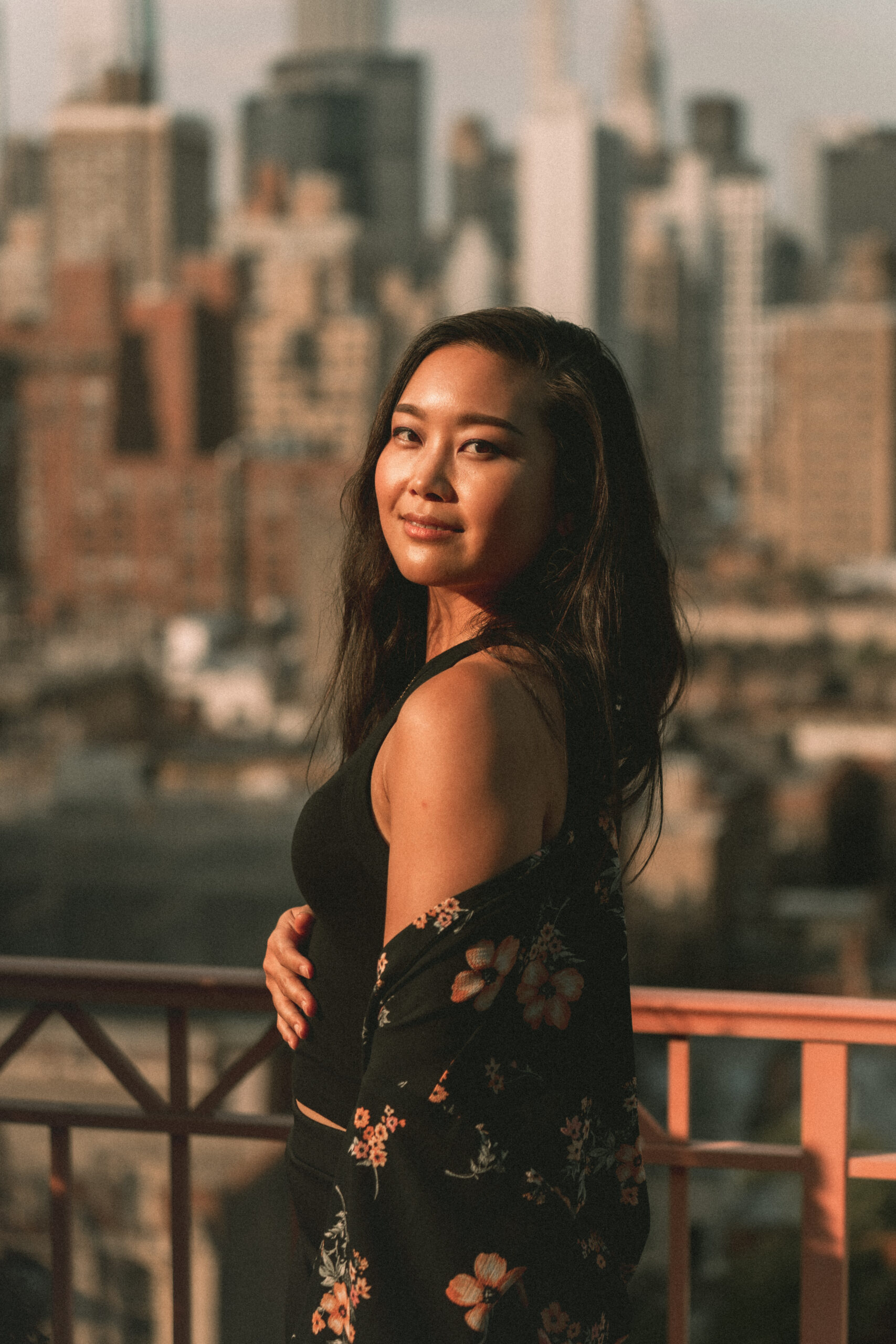 Jessica Hwang in a black and floral top standing in front of the New York skyline