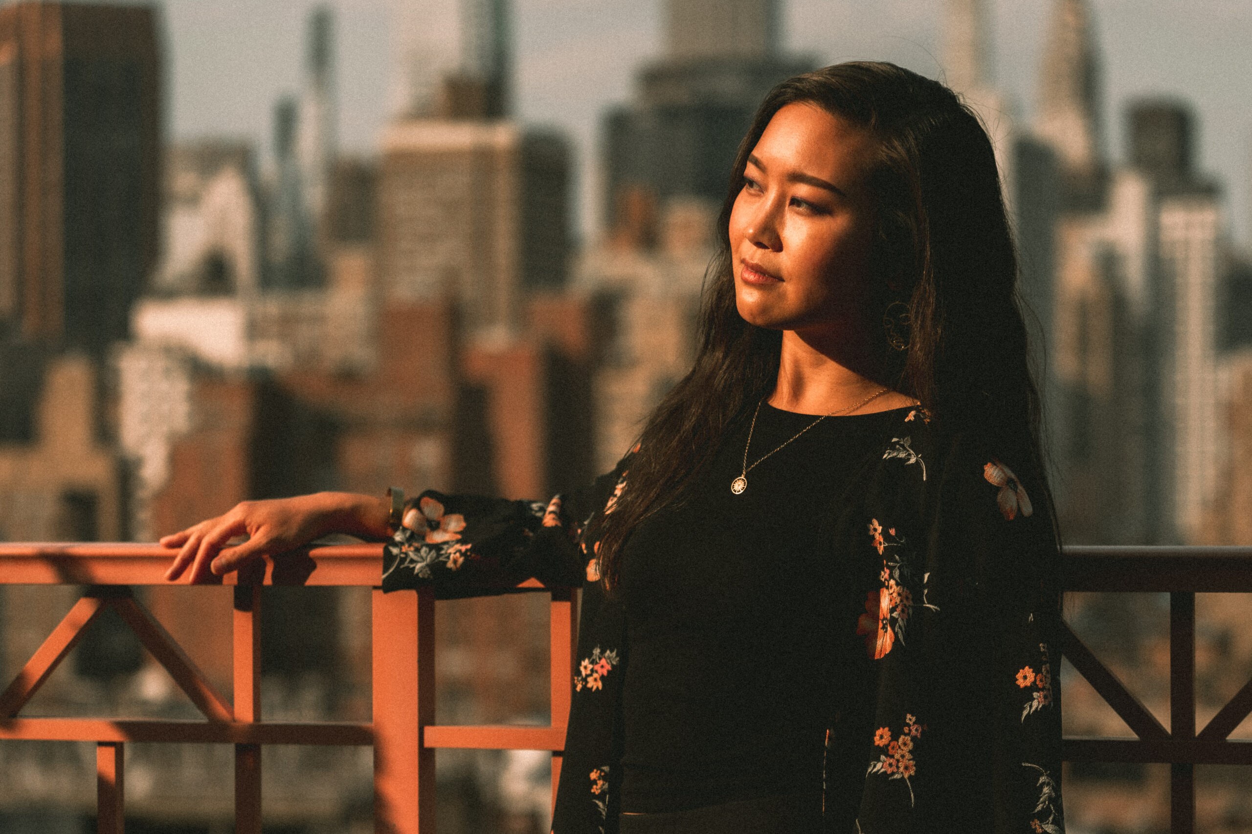 Jessica Hwang gazing at the sunset in front of the new york city skyline